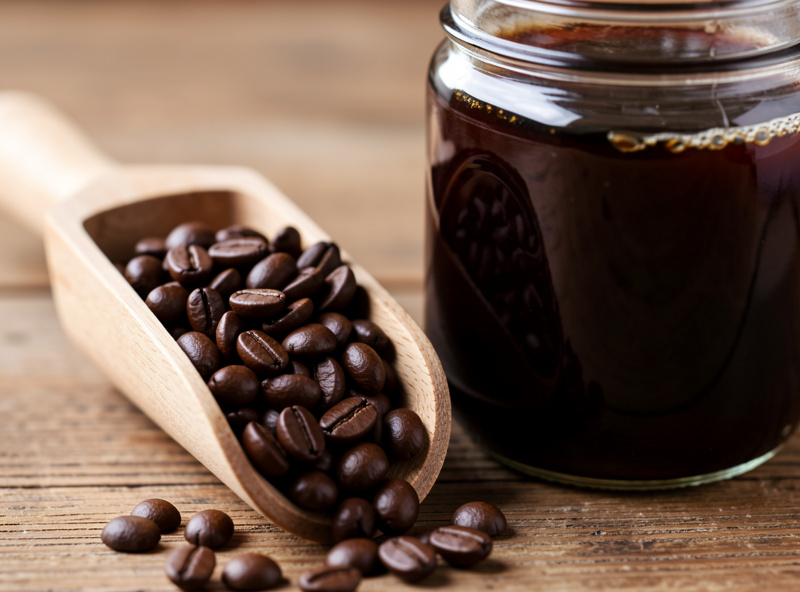 Bag of medium-dark roast coffee beans next to a jar of dark cold brew concentrate
