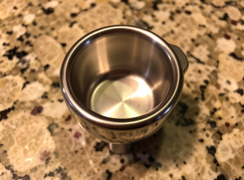 A 58mm bottomless portafilter fitted with a precision basket on a counter