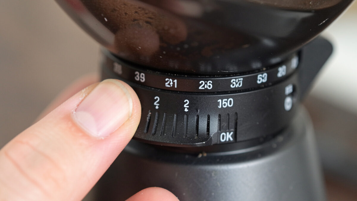 Close-up of a grinder adjustment collar showing stepped click positions versus a stepless dial for espresso