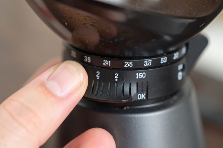 Close-up of a grinder adjustment collar showing stepped click positions versus a stepless dial for espresso