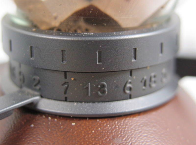Close-up of an espresso grinder adjustment collar with markings, showing the grind size dial