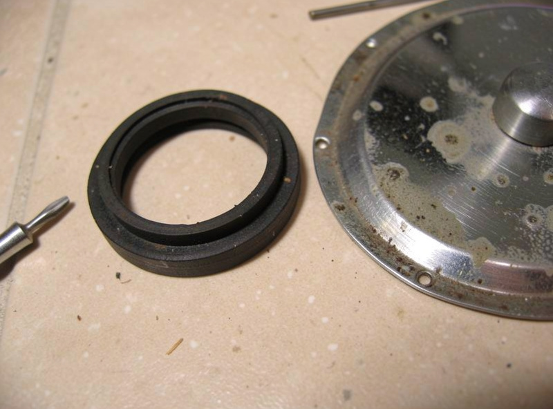 Close-up of a worn group gasket and shower screen removed from a used espresso machine group head
